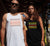 Male and Female outside a house wearing  Singlet tank T Shirts.  He is wearing white with the Graphic of stacked words in shades of orange and brown.  She is wearing a Black singlet tank t-shirt with graphics in shades of yellow and red. The text reads Imagine, repeated 3 times, create, innovate.