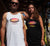 Male and female outside a house wearing singlet tank t shirts.  He is wearing white, she is wearing black.  Text is Carnarvon, Westerm Australia.  Graphic of palm trees and birds in silhouette against a sunset.
