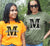 Two females in a garden wearing orange or khakit fitted Short Sleeve T Shirt. Graphic large letter M. The text reads Metacognition, think about your thinking.