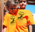 Boy and girl wearing orange short sleeve t-shirt.  Design is in black.  The graphics are of a silhouette of a kite surfer with the text Wind Riders, Carnarvon Western Australia,
