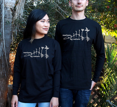 Male and Female wearing Black Long Sleeve T Shirts. The design is in white. The graphic is an outline image of a seed growing in stages. The text is nurture by nature.