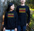 Male and Female outside in a garden wearing Long Sleeve Black T Shirts.  Graphic is stacked words in shades of yellow and red.  The text reads Imagine, repeated 3 times, create, innovate.