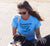 Female on the beach with dog wearing a Light Blue fitted short sleeve T-shirt.   Design in black.  Graphic is a silhouette of a kite surfer with the text Carnarvon Western Australia.  It's all About the Summer Wind.