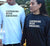 Male and Female in a garden wearing Long Sleeve T Shirts. She is in black with white graphic. He is in white with black graphic. Graphic is stacked words. The text reads Listening with Empathy.