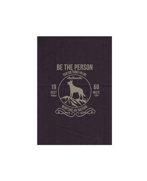 Grey Tea Towel with design. The graphic is one colour.  There is a circle outline with a silhouette of a dog standing on a rocky outcrop.  Around the circle the text says - Be the person your dog thinks you are, Nurture by Nature.  On either side of the circle there is text that is split - it says 19-69, Best Mate, Wild Life