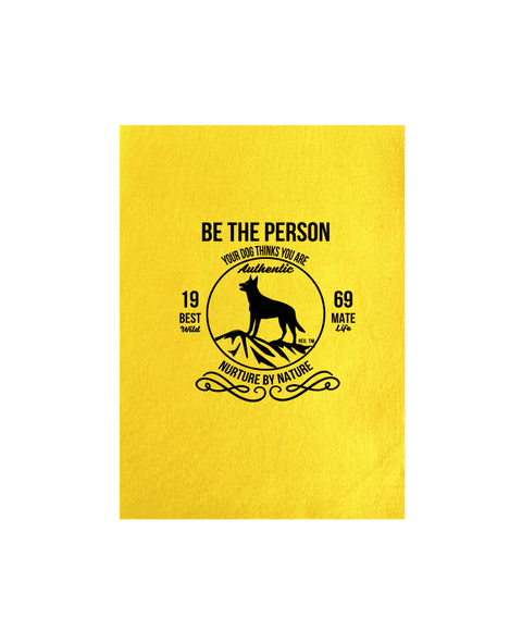 Yellow Tea Towel with design. The graphic is one colour.  There is a circle outline with a silhouette of a dog standing on a rocky outcrop.  Around the circle the text says - Be the person your dog thinks you are, Nurture by Nature.  On either side of the circle there is text that is split - it says 19-69, Best Mate, Wild Life