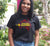 Female wearing a fitted short sleeve black t shirt.  Graphic is a map of Australia with Tribal Boundaries in Red.  There is text overlay in yellow that reads Always Was, Always Will Be.  Yamatji Country is highlighted.