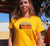 Female wearing a Golden Yellow Short Sleeve Fitted t shirt with graphic design of a silhouette of a kelpie dog with the text Best Mate on the Side of Adventure