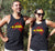 Male and Female wearing  Black Singlet T - shirt - with graphic - of australia map in traditional boundaries - in red.  Overtop of the map are the words Always Was Always Will Be, written in yellow. Yamatji COuntry highlighted.